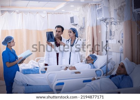 Doctor examining senior patient in critical health conditions and examining the x ray in the intensive care unit Royalty-Free Stock Photo #2194877171