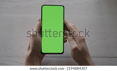 Man using phone with green screen on white oak table , wide photo