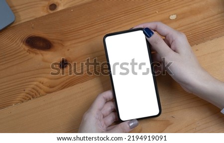 hand woman using a telephone, empty screen smart phone and computer on wooden table top view.