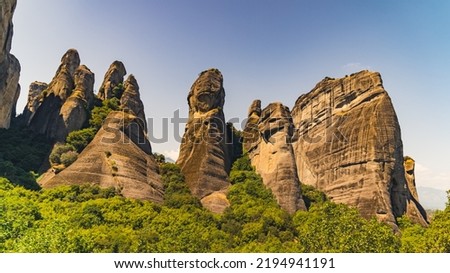 Stunning natural rock formations of Meteora, Greece covered halfway with green trees and bushes. Clear sky. High quality photo