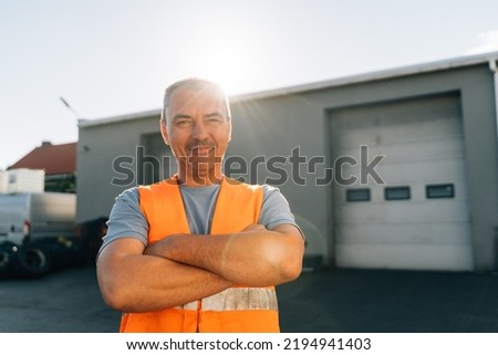 Portrait of caucasian mature man on semi-truck vehicles parking background. Truck driver worker  Royalty-Free Stock Photo #2194941403