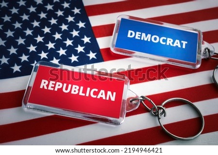 the keychain of the Republican Party and the Democratic Party on the background of the US flag. Opposition of Republicans and Democrats concept. Elections in the United States of America.