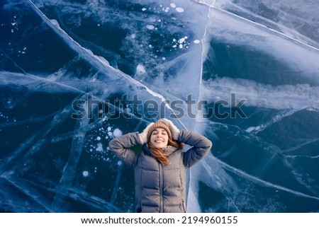 Travel winter Lake Baikal, happy joy woman tourist lie on ice sunset, top view. Royalty-Free Stock Photo #2194960155