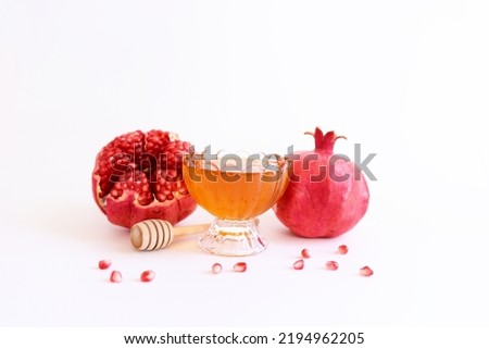 Rosh hashanah (jewish New Year holiday) concept. Pomegranate and honey traditional symbols over white background Royalty-Free Stock Photo #2194962205