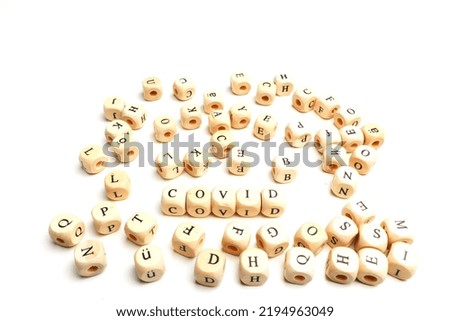 letter cubes lying chaotic on white table. Isolated on white. Some cubes building two words: Covid