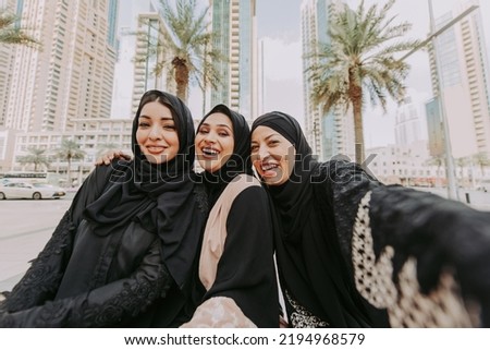 Arabic women with abaya bonding and having fun outdoors - Happy middleastern female friends with traditional muslim dresses meeting and talking while shopping
