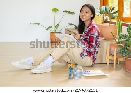Young girl sitting on the floor and painting on paper at home. Hobby and art study at home.