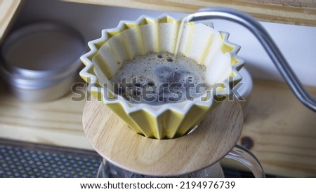 It is a picture of a drip coffee with coffee beans in a cone with filter paper.