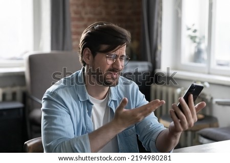 Angry frustrated mobile phone user man getting problems with online app work, Internet bank service failure, reading notice with bad news, holding smartphone, looking at screen, feeling stress Royalty-Free Stock Photo #2194980281