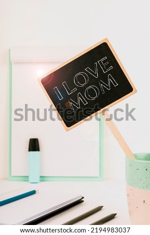 Conceptual caption I Love Mom. Conceptual photo Good feelings about my mother Affection loving happiness Small Blackboard With Important Message In Cup On Desk With Clipboard.