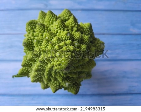 Romanesco broccoli, Roman cauliflower, Romanesque cauliflower, or simply Romanesco, and sometimes Broccoflower on a wooden table, viewed from above.