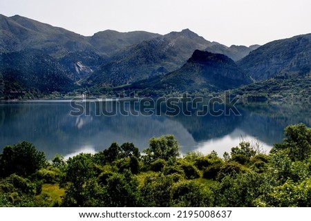 Scenic view of mountains reflecting on a lake in Northern Spain. Peaceful and tranquil setting with shadows across the hills and valleys.