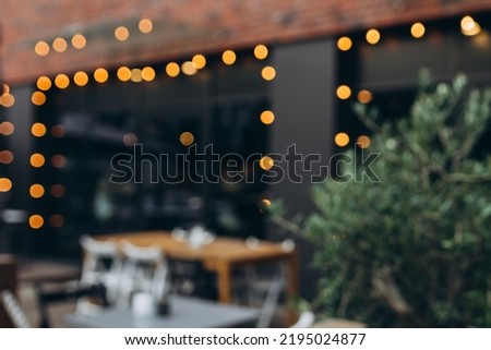 Blurred background of outdoor restaurant with abstract bokeh light. Outdoor cafe with tables and chairs Royalty-Free Stock Photo #2195024877