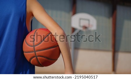 The teenager plays basketball. Healthy lifestyle and hobby concept. Cute kid hitting a basketball ball. Slow motion street basketball. Boy practicing shooting a basketball