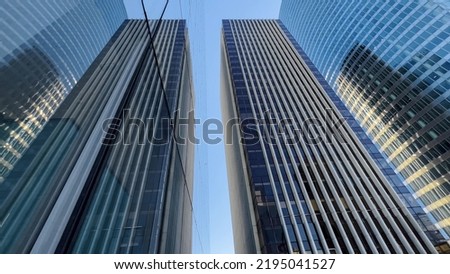 Building reflected on glass skyscraper in Paris, grey skyscraper in Paris, open glass at left, blue sky and reflections. Wide Shot.