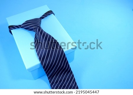 striped necktie isolated on blue background with gift box father's day concept 