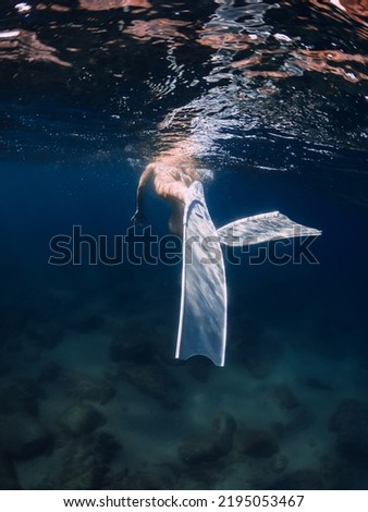 Woman with white fins swimming in deep blue ocean Royalty-Free Stock Photo #2195053467