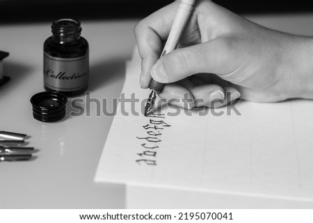 The process of writing calligraphy by hand with pen and ink. High quality black and white photo