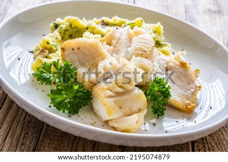 Fish dish - fried cod fillet with potato puree on wooden table
