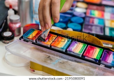 a hand with a brush picks up rainbow bright multicolor paint