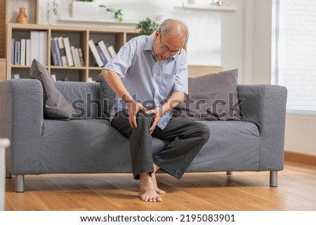 close up hands man with his knee joint pain in sofa, pain in the elderly, health care.Grandfather with knee pain Royalty-Free Stock Photo #2195083901