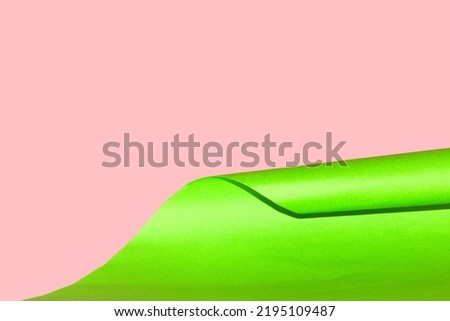 green paper wrapping on pink background, creative art design, copy space green wave