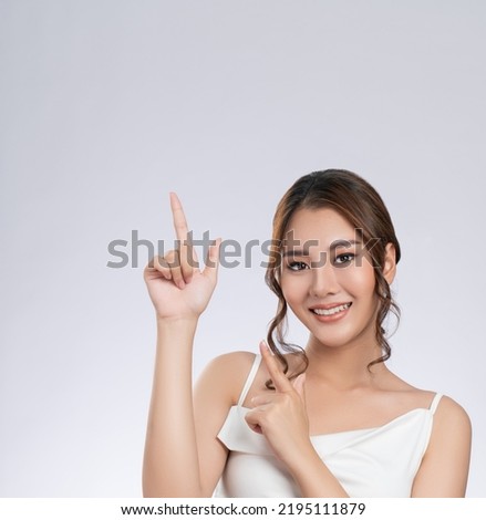 Photo of a gorgeous woman with flawless healthy fresh skin in a concept of empty space for beauty care product. Skincare product, model uses hand to create empty space for commercial.