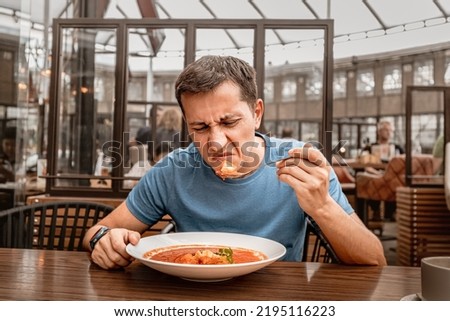 dissatisfied unhappy customer of the restaurant sniffs the disgusting smell of a bowl of soup with spoiled ingredients and is going to complain to the chef Royalty-Free Stock Photo #2195116223