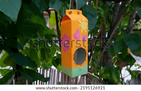 Homemade Bird Feeder in a tree. Milk Carton Bird House in a tree      Royalty-Free Stock Photo #2195126921