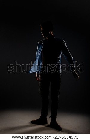 Sideview of an handsome model taking off his shirt and posing inside the studio