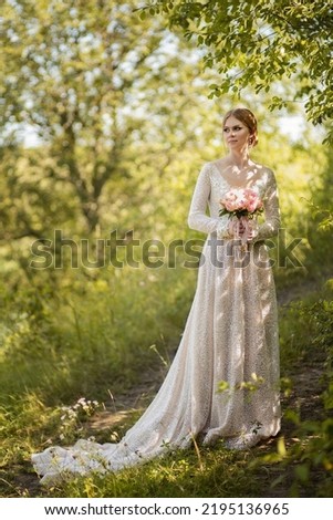 Photo of a bride in a wedding dress with a bouquet of pink roses.