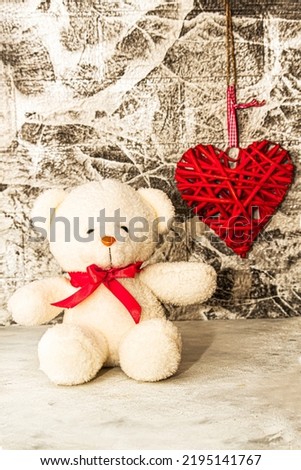 White Teddy bear with red heart on grey wall background. Rattan work of heart shape