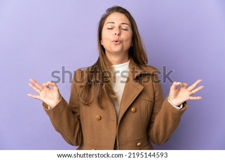 Middle age Brazilian woman isolated on purple background in zen pose