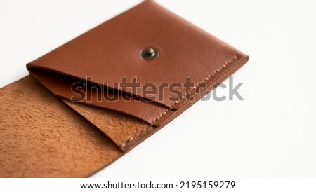 Opened empty orange genuine leather card holder on a white surface.