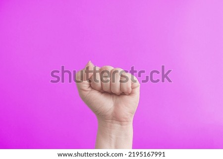 Female fist on a pink background. The concept of feminism and the struggle for women's rights.