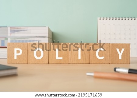 Wooden blocks with "POLICY" text of concept, pens, notebooks, and books.