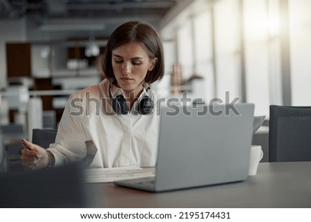 Business woman working laptop and making notes while sitting in modern office. Blurred background
