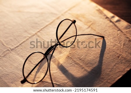 Vintage eyeglasses on an old paper.  Low key incandescent lighting. Shallow depth of field. Royalty-Free Stock Photo #2195174591