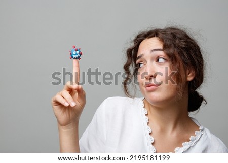Young woman holds the puppet of a COVID-19 virus on her finger without any fear; concept of the new normal and the power of science and knowledge