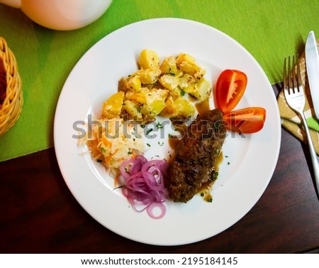 Delicious meat dish lula-kebab with stewed potatoes, pickled cabbage, onions and fresh tomatoes...
