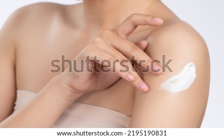 Close up gorgeous girl with soft makeup applying moisturizing skincare cream on shoulder isolated over white background. Skincare cream applied by female model concept. Healthy clean fresh skin. Royalty-Free Stock Photo #2195190831