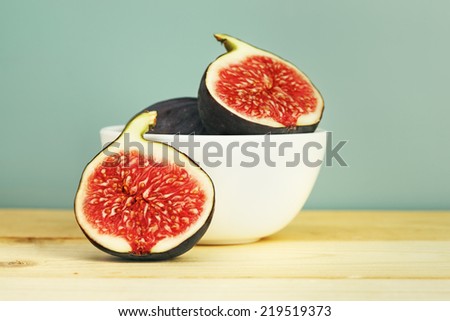 fresh figs in a bowl on wooden table, retro blue background  Royalty-Free Stock Photo #219519373