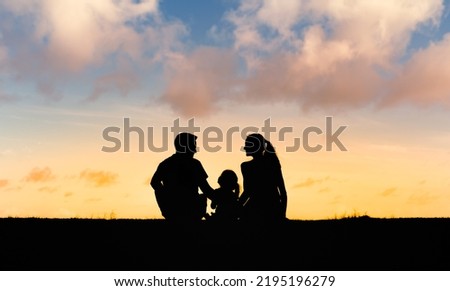Silhouette of a family enjoying a beautiful sunset. Parenting and family lifestyle concept. 
