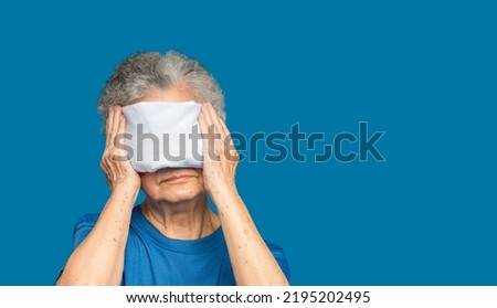 Senior woman using hot compress gel on eyes while standing on a blue background. Nasolacrimal duct obstruction. Cataract disease, etc. Space for text. Aged people and healthcare concept Royalty-Free Stock Photo #2195202495