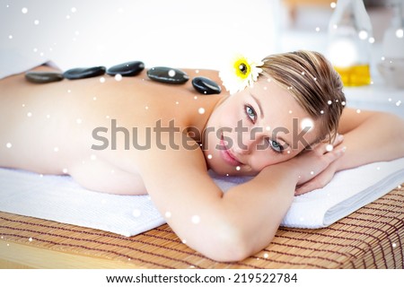 Glowing young woman with hot stone on her back smiling at the camera against snow