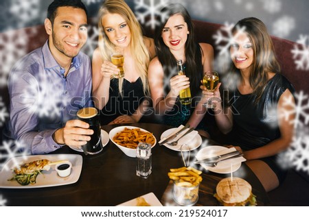 High angle view of happy friends having dinner together against snowflakes