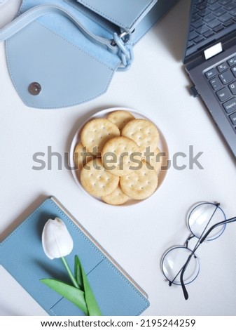 Snack time photography concept. Consist of blank book, blue pen, glasses, laptop, mobile phone and sandwich cracker on plate. Isolated background in white