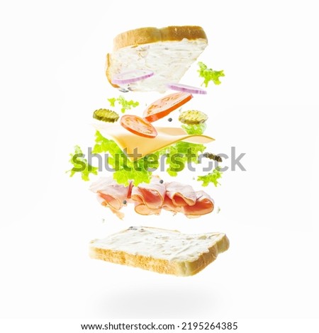 Appetizing hamburger on a light background in a frozen flight. Meat, cheese, greens and pieces of vegetables in a state of levitation. Advertising, banner. There are no people in the photo.