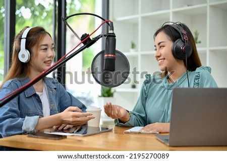 Two attractive and  professional young Asian female radio host working together in the studio, enjoys running their podcast show as a team.