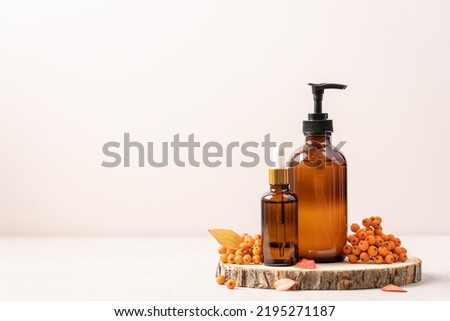 Set of beauty cosmetics on podium from saw cut tree with autumn leaves and rowan berries. Autumn concept of skincare, fall sales, Thanksgiving cosmetic gifts